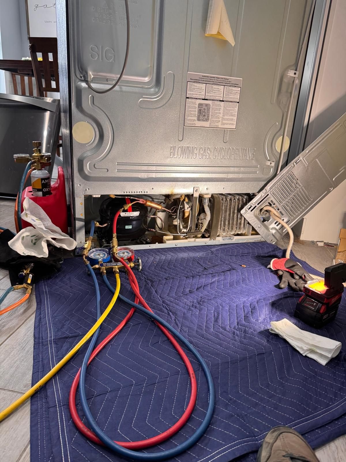 Refrigerant manifold gauges connected to a refrigerator sealed system during a repair
